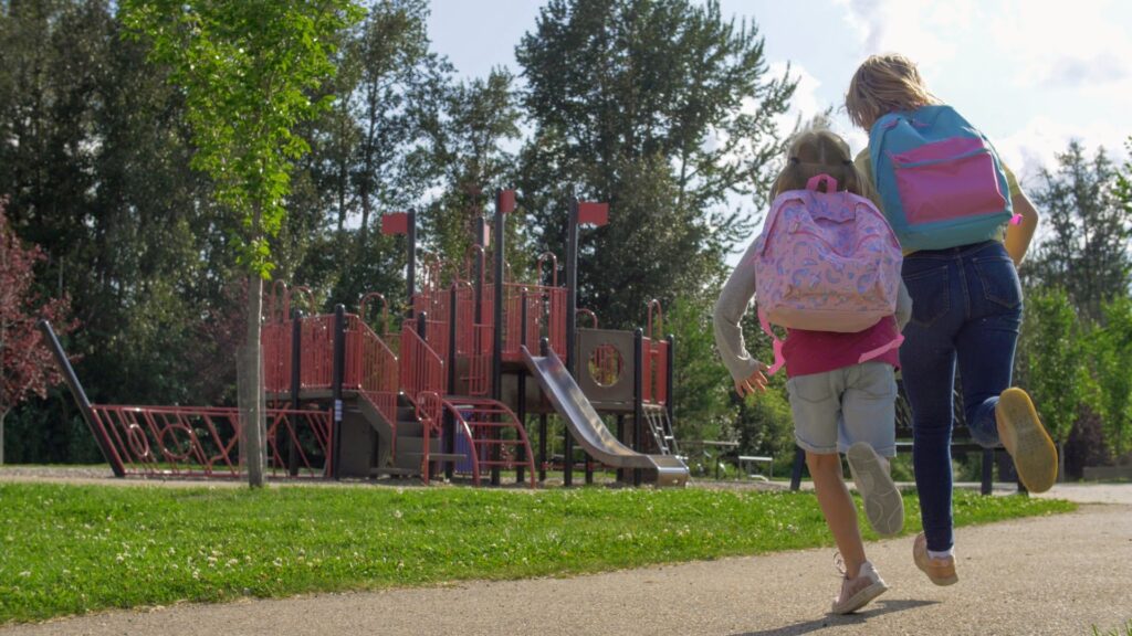 2 children run towards a playground