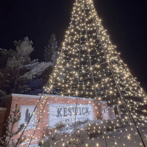 a tree of lights in front of Keswick sign