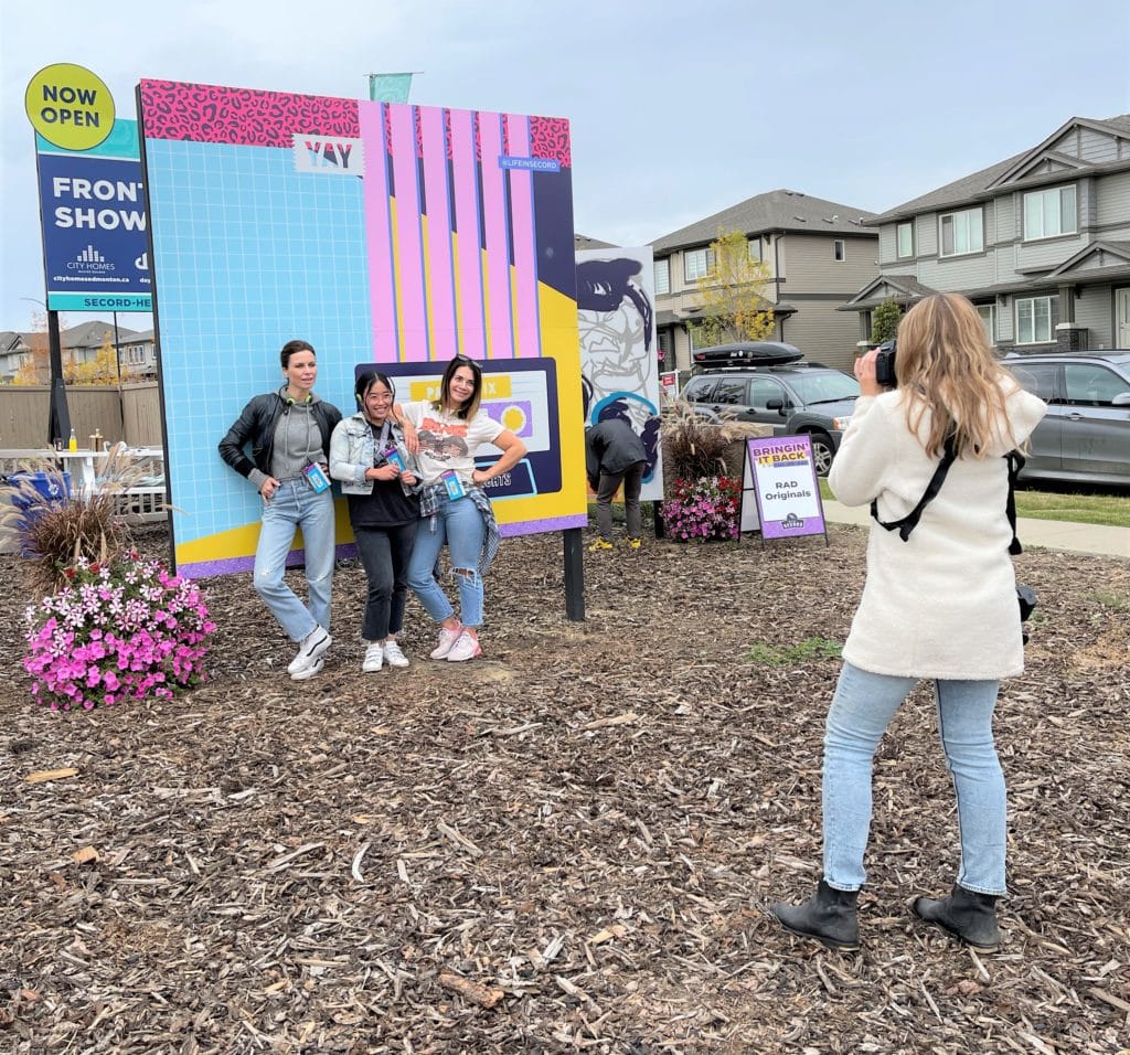 3 friends pose in front of an instagram backdrop wall in Secord Heights
